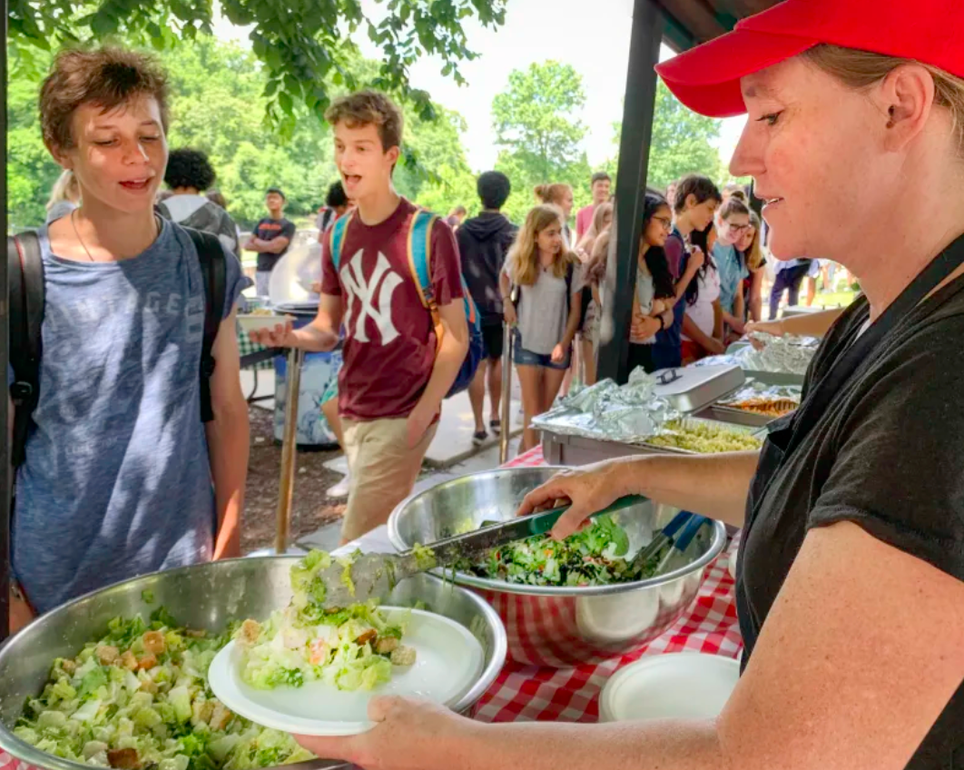 WIS parent Katie Huffard serves Caesar salad to senior Matteo Caloia during Parent Grill. Due to COVID-19, Parent Grill hasn’t operated since early 2020 (Jen Packard/wis.edu).
