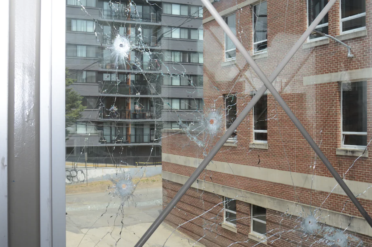 Shattered windows surrounding the Edmund Burke Schools glass bridge. On April 22, a shooter fired hundreds of rounds at this walkway from his apartment building, pictured on the left. (Courtesy of D.C. Metropolitan Police Department)