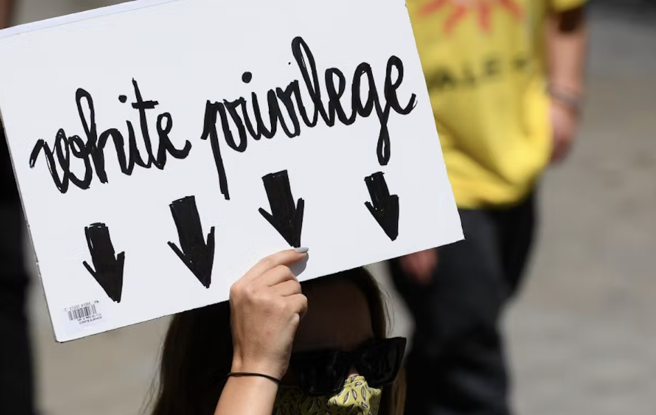 A protestor holding a sign with the words White Privilege at an event protesting police brutality in Spain. WIS seventh graders recently discussed the notion of white privilege in an English class activity called privilege math. (Josep Lago/AFP)